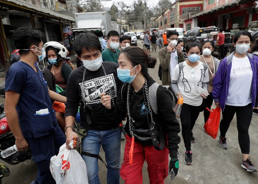 Animal volunteers wear gas masks as they search for pets left by owners who fled to evacuation centers in Talisay, Batangas province, south of Manila, Wednesday. AP