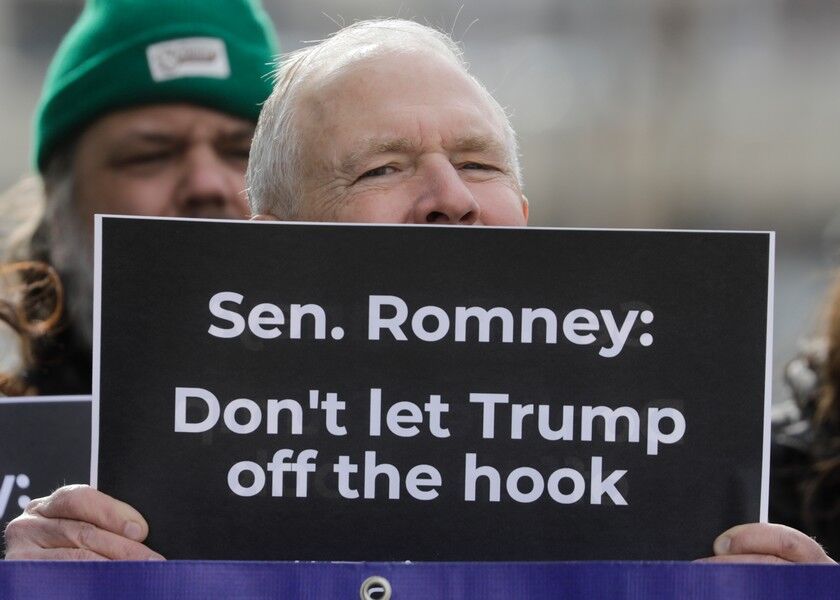 Scott Riching joins others outside the office of Sen. Mitt Romney to call on him to push for a full and fair impeachment trial in the Senate with pertinent testimony and evidence during a rally, in Salt Lake City on Jan. 16, 2020. Republican Senator Romney is having another big moment as he defies Republican leaders at President Donald Trump’s impeachment trial. Romney is one of several GOP senators insisting on hearing from witnesses. AP