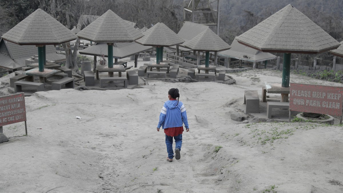 A woman walks along a park covered in volcanic-ash at a town near Taal volcano in Tagaytay, Cavite province, south of Manila on Jan. 19, 2020. AP