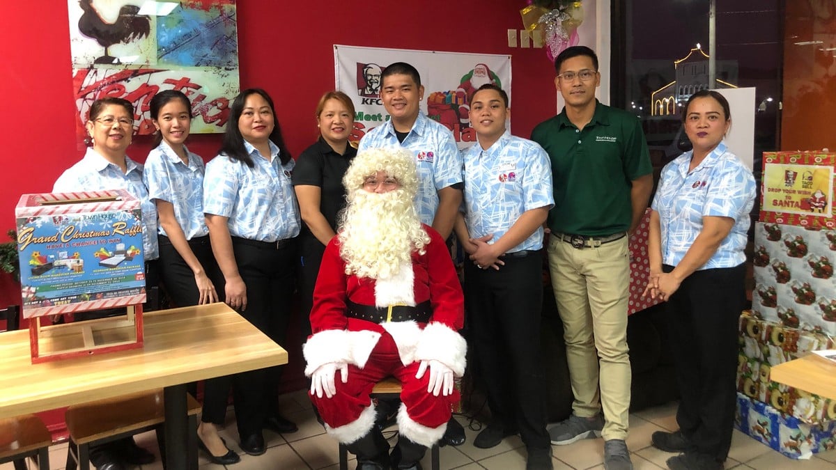 KFC/Taco Bell and Townhouse employees, from left, Imelda Valiente, Nicole Perez, Marie Candado, Yole Aldan, Benedict Pineda, Jerome Perez, Rodman Diaz, Anna Guinto, and Jhon Raymart Reyes, center front row, as Santa Claus pose for a picture during the raffle draw at KFC in Susupe on Dec. 31, 2019. Photo by Dads Maluyo