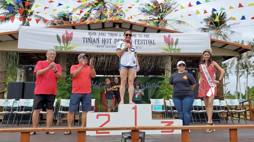 Kimberlyn King-Hinds, center, wins the hot pepper eating contest for females on Tinian, Saturday. Also in photo are Rep. Leepan Guerrero, Tinian Mayor Edwin Aldan, Marianas Visitors Authority Managing Director Priscilla Iakopo and Miss NMI Earth-Fire Katherine Maria Johnson. Photo by Junhan B. Todiño