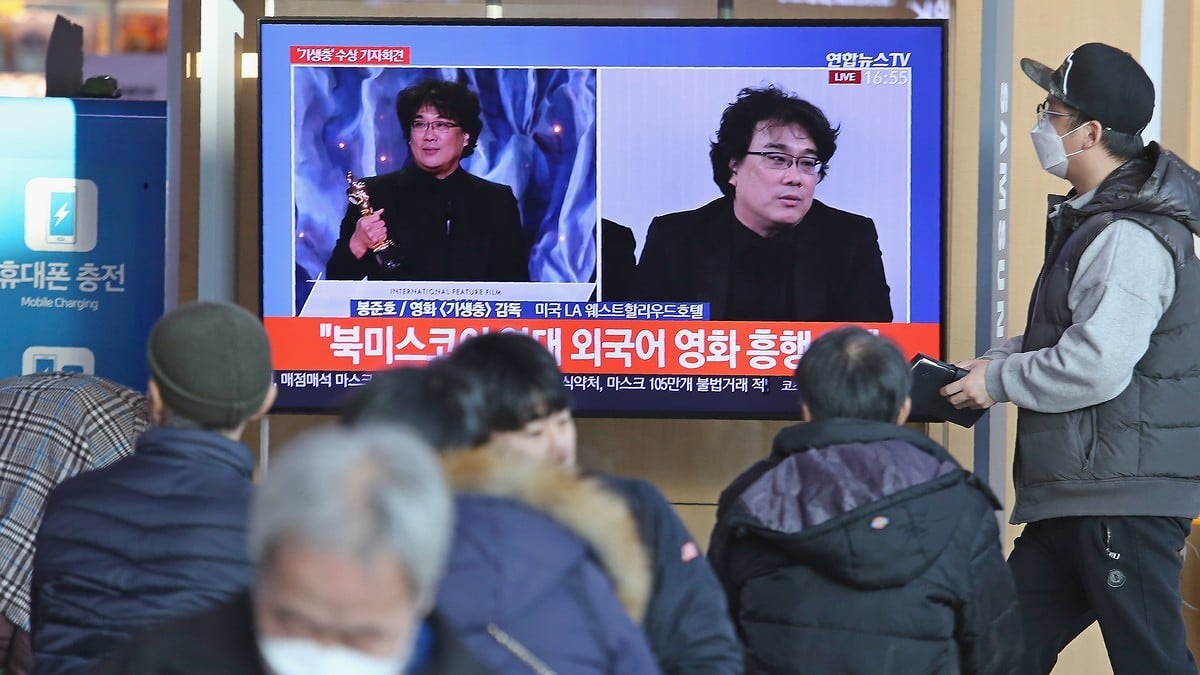 People watch a TV screen showing images of South Korean director Bong Joon Ho during a news program at the Seoul Railway Station in Seoul, South Korea, Monday. In a milestone win that instantly expanded the Oscars’ horizons, Bong’s masterfully devious class satire “Parasite” became the first non-English language film to win best picture in the 92-year history of the Academy Awards. The signs read: “Foreign language movie.” AP