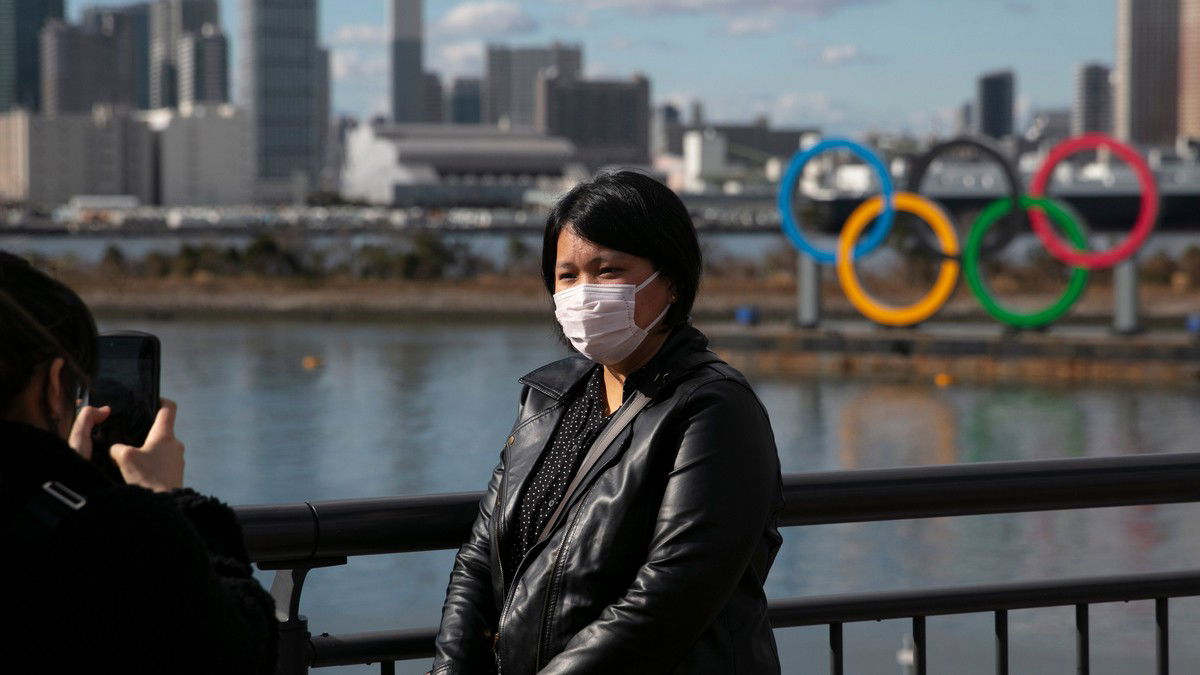 In this Jan. 29, 2020, file photo, a tourist wearing a mask poses for a photo with the Olympic rings in the background, at Tokyo’s Odaiba district. Tokyo Olympic organizers repeated their message at the start of two days of meetings with the IOC: this summer’s games will not be cancelled or postponed by the coronavirus spreading neighboring China. AP