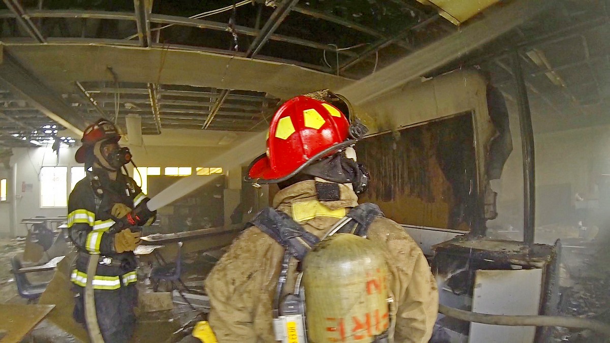 A firefighter directs a stream of water from a fire hose at flames inside one of the typhoon-damaged buildings of Hopwood Middle School on Monday afternoon. DFEMS photo