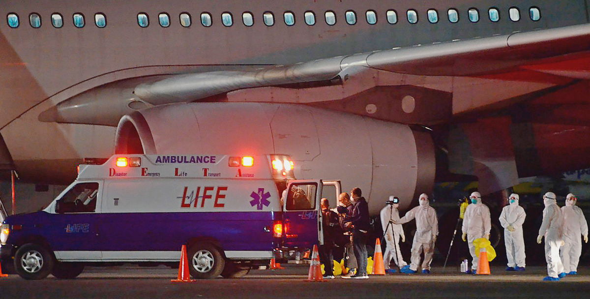 Staff members of the Department of Foreign Affairs and the Department of Health wear protective suits as they assist Filipinos from the Diamond Princess Cruise Ship who arrived at the Clark airbase, Pampanga, north of Manila, early Wednesday. AP