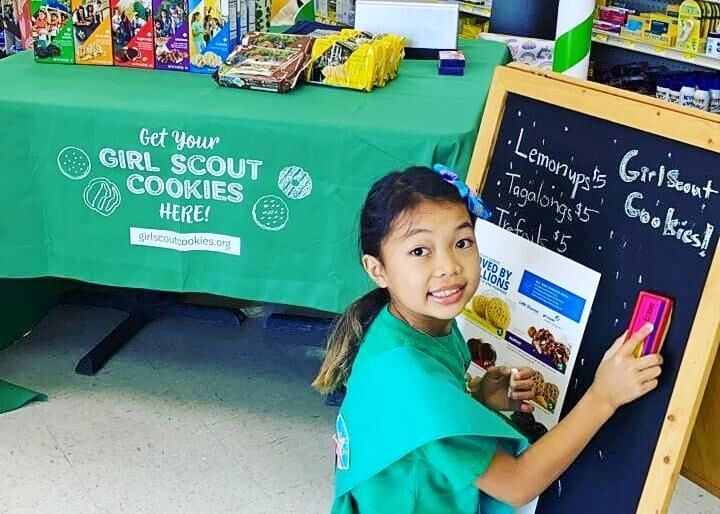 NMI Girl Scout Junior Emma Sablan prepares the chalkboard sign at her cookie table at Joeten Dandan on Saturday morning. Contributed photo