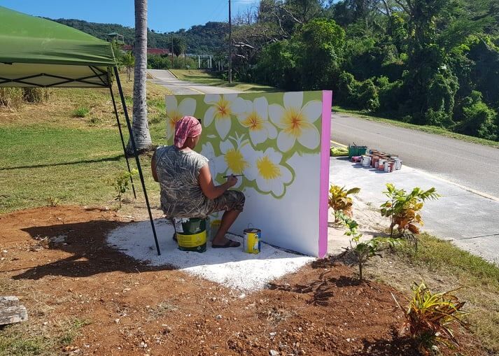 A staff member of Rep. Joel Camacho paints a new beach sign. Contributed photos