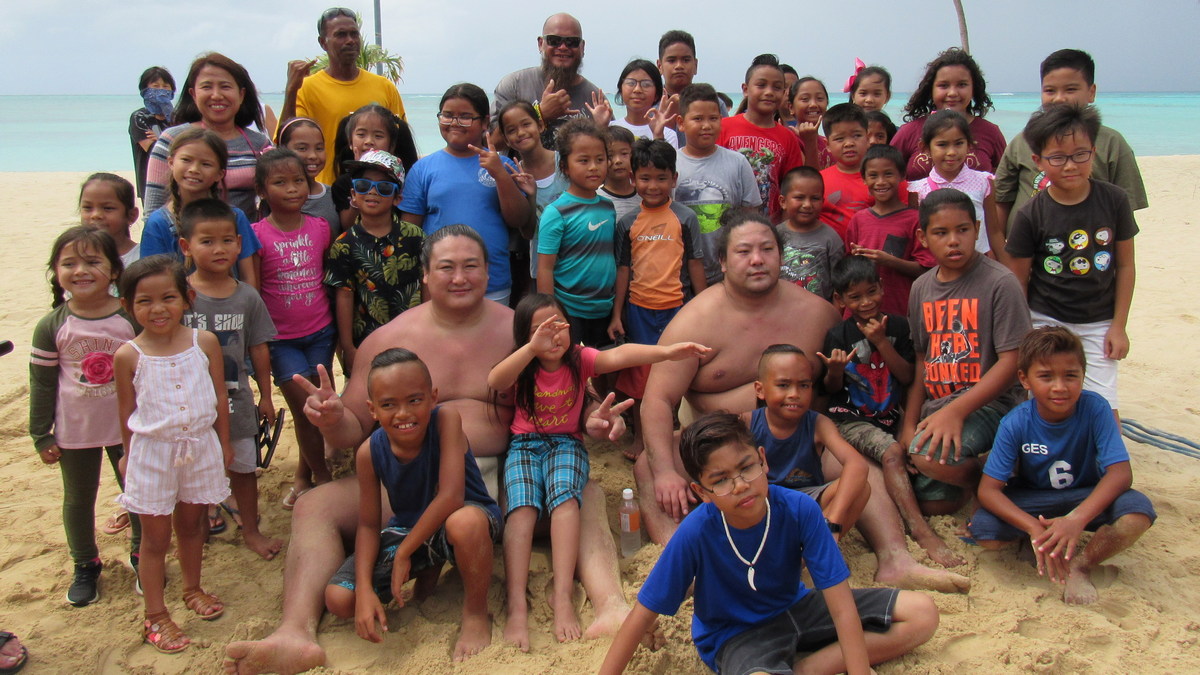 Sumo wrestlers Kyokutaisei Takuya and Kyokushiuho Koki  pose with children and other local fans at the Hyatt beach on Saturday afternoon. Photo by Prince Factor