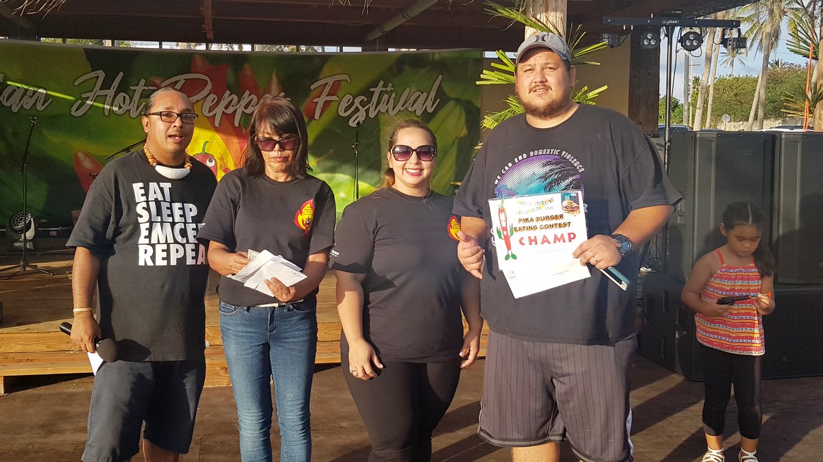 Thomas Erickson, right, who has just returned to Tinian after five years in the states, is this year’s pika burger eating contest winner. With him in the photo are Marianas Visitors Authority Managing Director Priscilla Iakopo, second right, MVA Tinian field operations supervisor Vida Borja, second left, and master of ceremonies Rep. Luis John Castro, left. Photos by Junhan B. Todiño