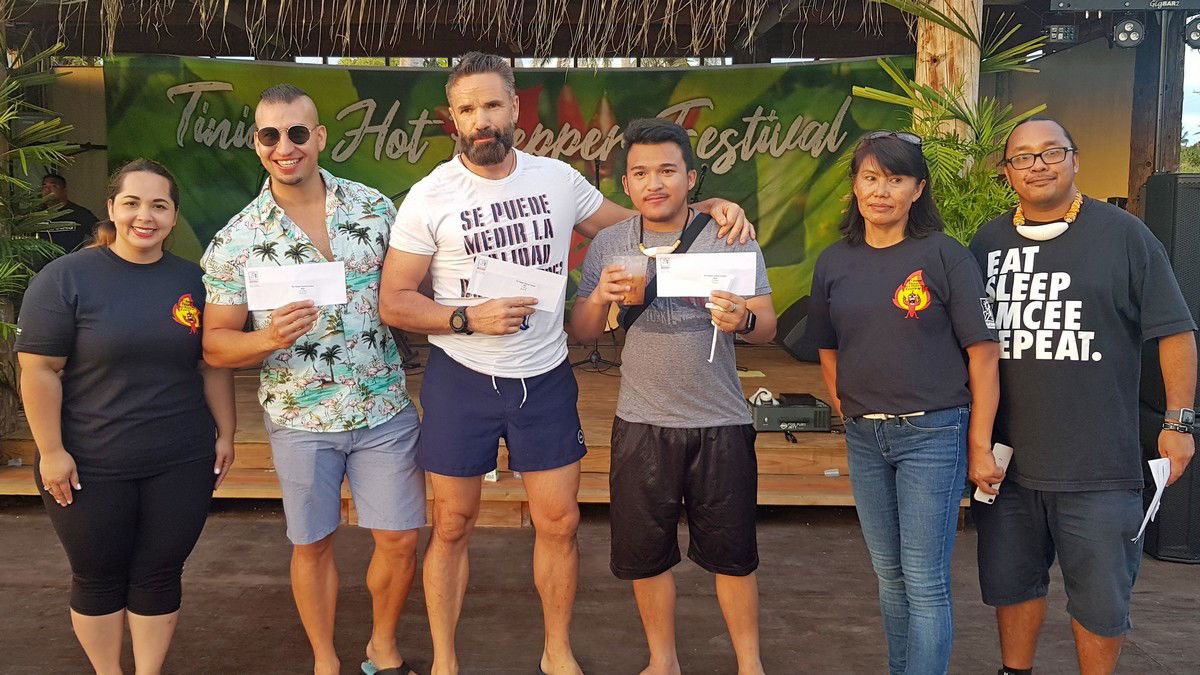 The winners of the hot-pepper eating contest: Vlad Melnik, third left, first place; Ahman Fadel, second left, second place; and Marc Soliva, third right, third place hold their checks while posing for a photo with Marianas Visitors Authority Managing Director Priscilla Iakopo, left, MVA Tinian field operations supervisor Vida Borja, second right, and master of ceremonies, Rep. Luis John Castro, right.