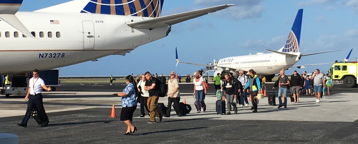 Passengers and crew leave a grounded United Airlines plane, right, after sleeping on the plane to board a “rescue” flight brought in by United March 19 at Amata Kabua International Airport in Majuro. Subsequently, United suspended regular service to the Marshall Islands. Photo by Giff Johnson