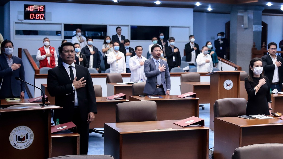 Philippine senators and government officials wearing protective masks place their hands on their chest during the singing of the national anthem at the start of a special session on a bill that would authorize Philippine President Rodrigo Duterte to appropriate a budget for measures addressing the new coronavirus situation Monday in Manila. AP