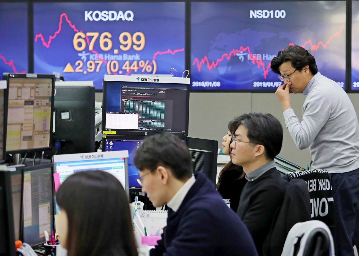Passersby wearing protective face masks following an outbreak of the coronavirus disease are reflected on a screen displaying stock prices outside a brokerage in Tokyo, Japan on March 17, 2020. REUTERS