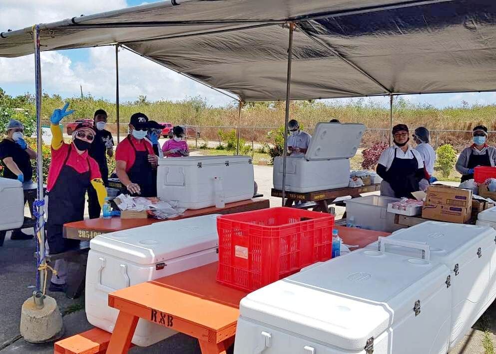 Triple J employees who are certified food handlers volunteer to distribute food to children on Wednesday at Garapan Elementary School. There are 30 Triple J volunteers who serve food at 10 distribution school sites.