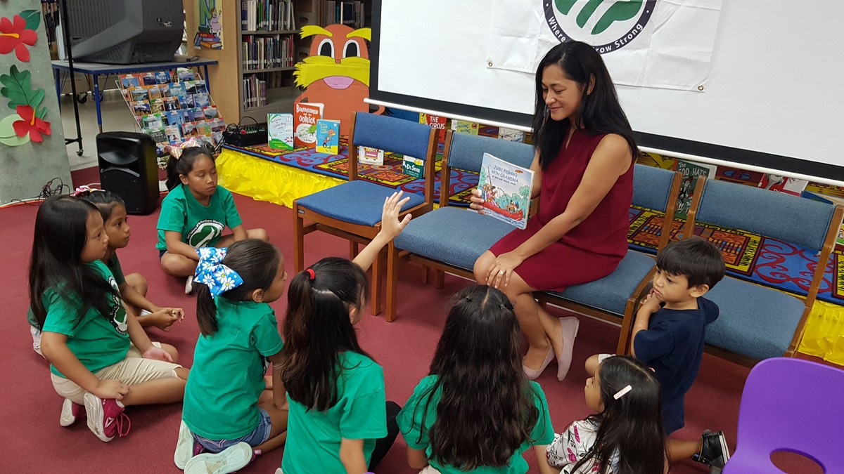 First lady Diann Torres shows a book to the NMI Girl Scouts at Joeten-Kiyu Public Library on Friday afternoon.