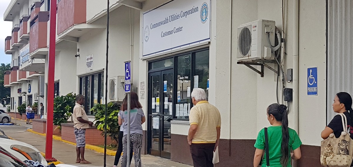 Community members keep their distance while waiting to get inside the customer service office of the Commonwealth Utilities Corp. at Joeten Dandan. Photo by Junhan B. Todiño