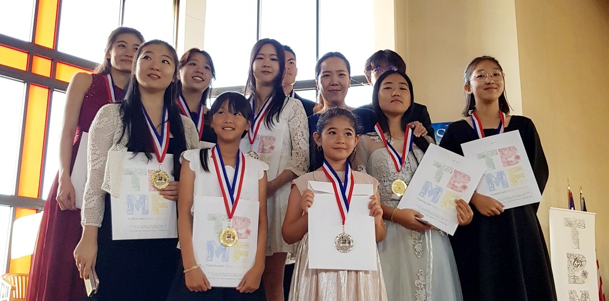 Yonsei Academy students pose for a photo after winning 8 gold and 5 silver medals at the Tumon Bay Music Festival. With them is their teacher and president Jihye Yun.
