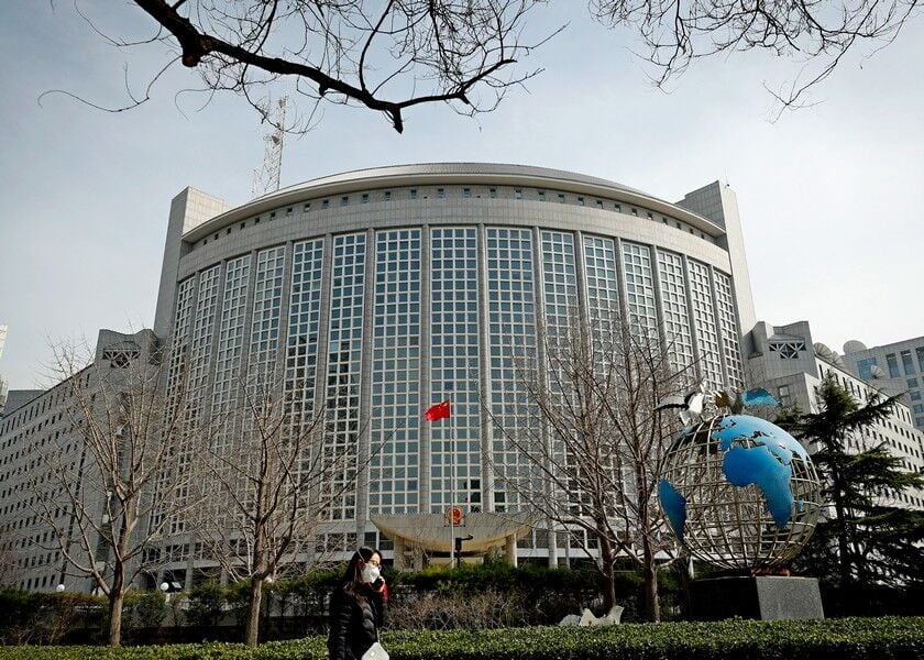 A woman wearing a protective face mask walks by the Ministry of Foreign Affairs office in Beijing, Wednesday. At least 13 American journalists stand to be expelled from China in retaliation for a new limit imposed by the Trump administration on visas for Chinese state-owned media operating in the U.S. AP