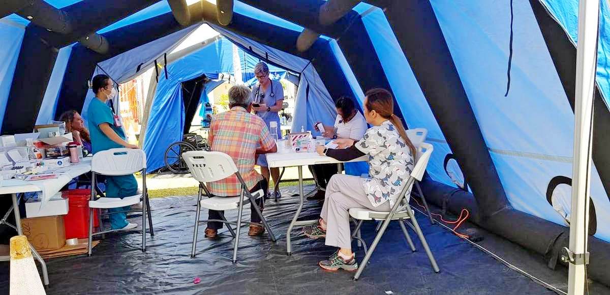 Commonwealth Healthcare Corp.-Family Care Clinic medical personnel conduct a screening for people with health concerns in a tent.