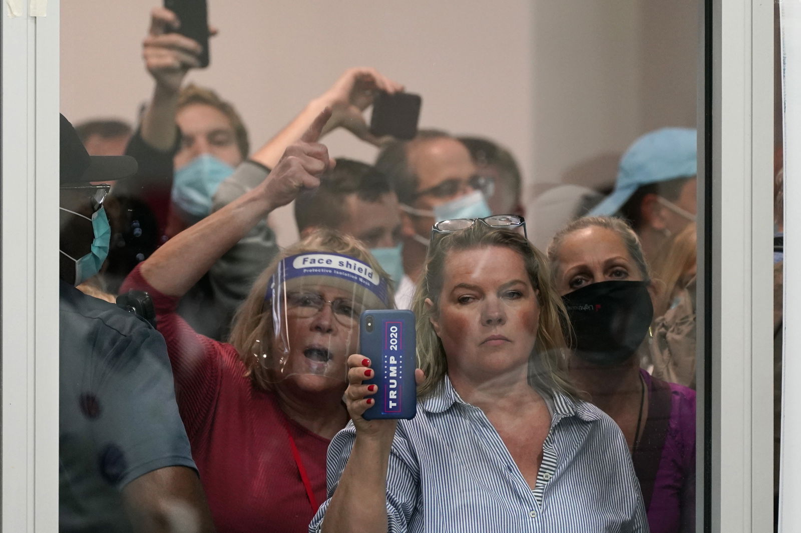 People wanting to be election challengers yell as they look through the windows of the central counting board as police were helping to keep additional challengers from entering due to overcrowding, Wednesday, Nov. 4, 2020, in Detroit. (AP Photo/Carlos Osorio)