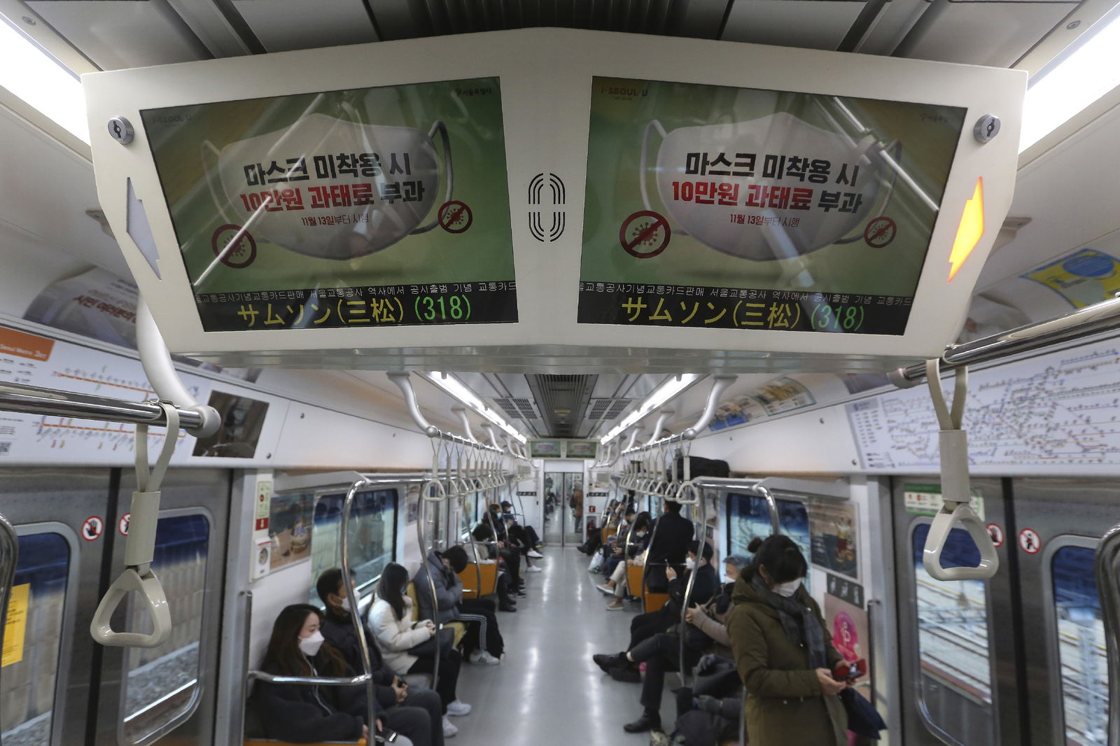 Digital screens showing precautions against the coronavirus are seen in a subway train in Goyang, South Korea, Monday, Nov. 30, 2020. South Korea is shutting down indoor gyms offering intense workout classes and banning year-end parties at hotels in the greater Seoul area to fight the virus. Prime Minister Chung Sye-kyun said Sunday. The banner reads: "People who do not wear masks in public will face a 100,000 won ($90) fine". (AP Photo/Ahn Young-joon)