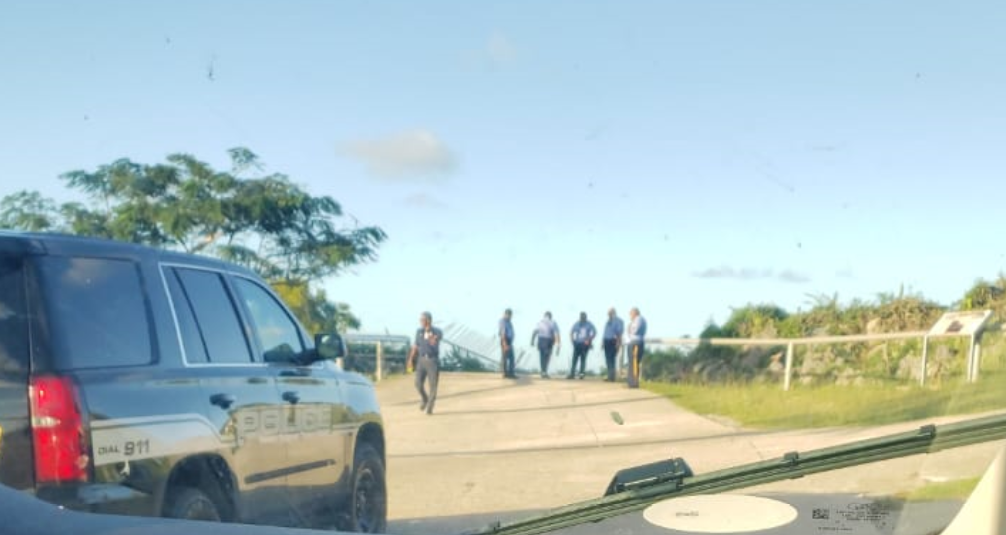 Police officers stand near the damaged railing at Suicide Cliff after a pickup truck drove off the cliff late Tuesday afternoon.