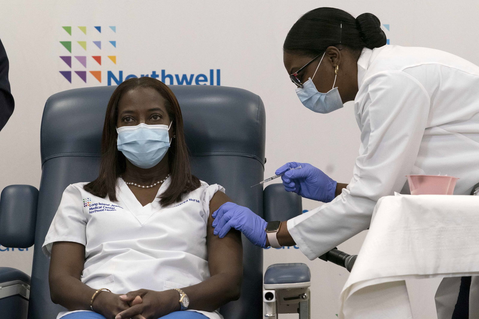 FILE - In this Monday, Dec. 14, 2020 file photo, Sandra Lindsay, left, a nurse at Long Island Jewish Medical Center, is inoculated with the Pfizer-BioNTech COVID-19 vaccine by Dr. Michelle Chester, Monday, Dec. 14, 2020, in the Queens borough of New York. (AP Photo/Mark Lennihan, Pool. File)