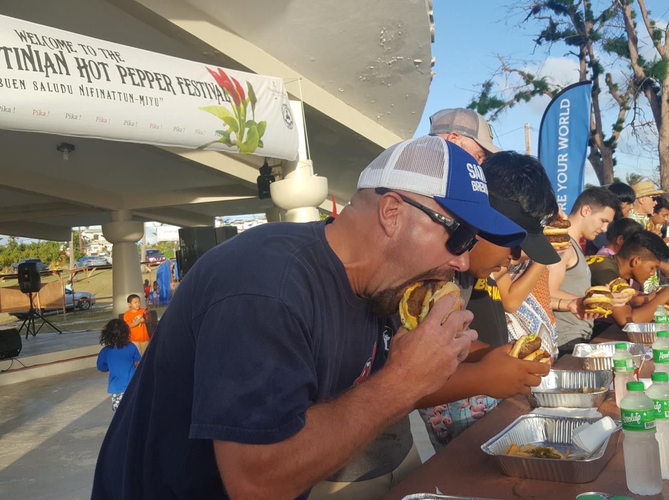 Competitors in the JC Café Pika Burger Eating Contest take their first bites at the 15th  Annual Tinian Hot Pepper Festival on  Feb. 16, 2019, in the  Marianas.   MVA photo