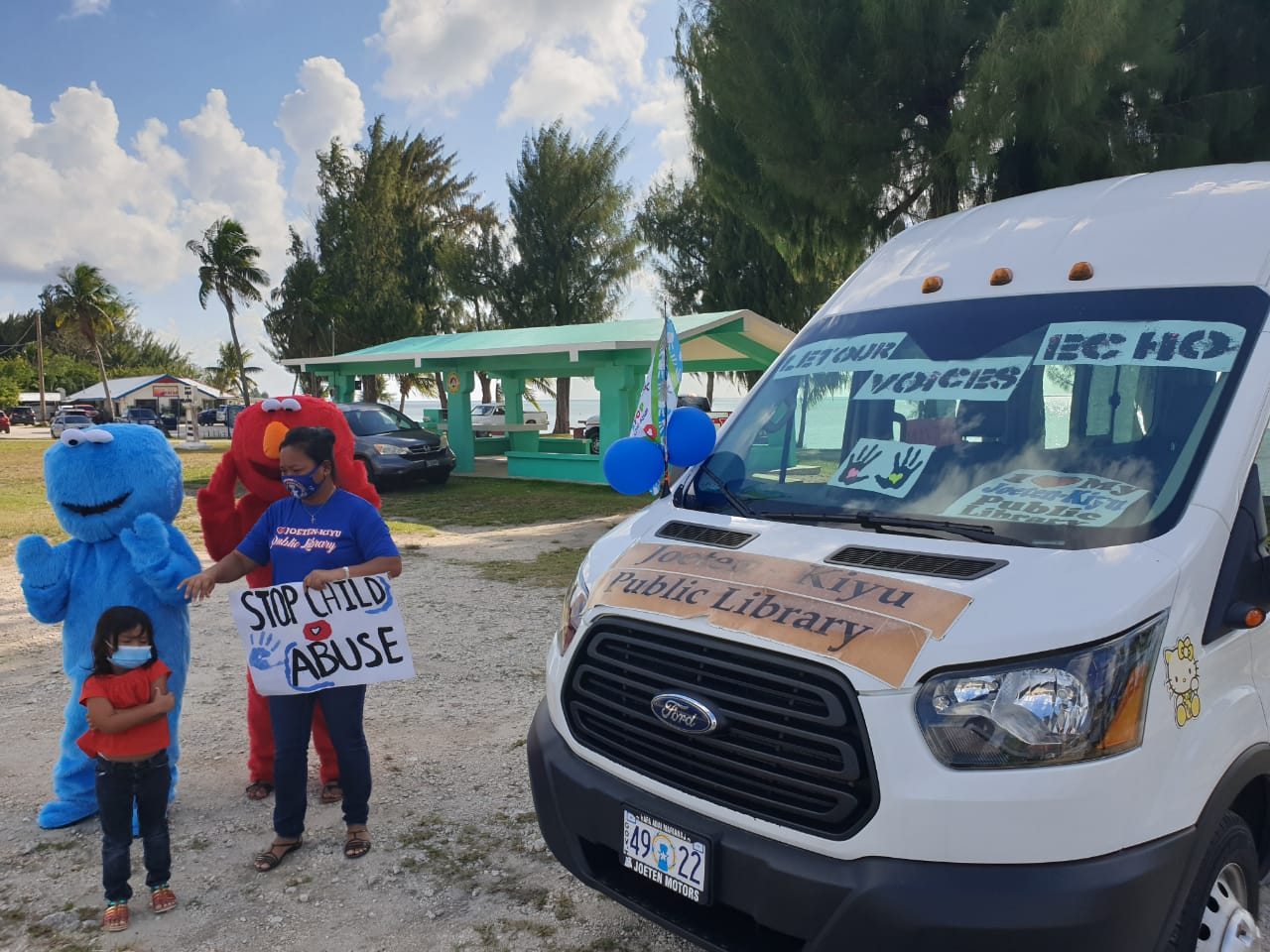 Joeten-Kiyu Public Library Executive Director Erlinda Naputi joins a child and mascots in the roadside waving activity on Friday at the Beach Road-San Jose intersection.Contributed photo
