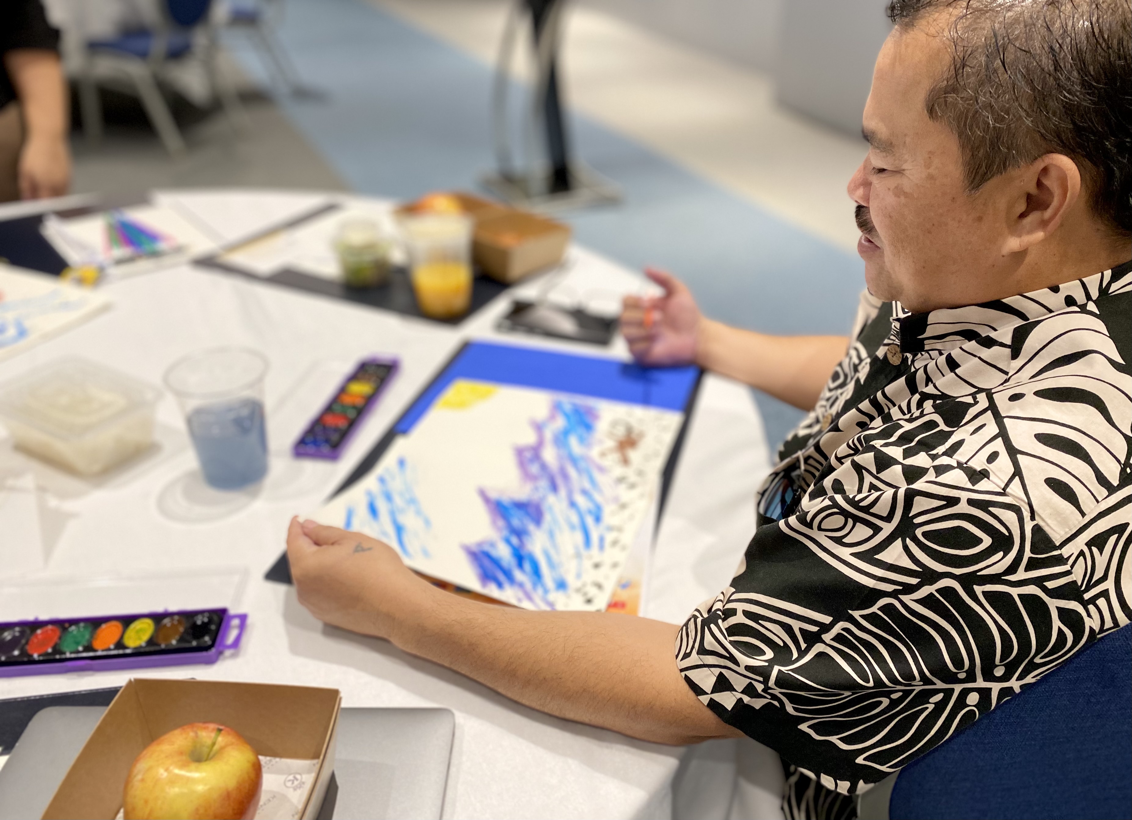 Commissioner of Education Dr. Alfred B. Ada looks at his water color painting during a stress-relieving activity.