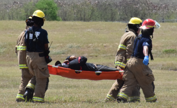 Two  Aircraft Rescue and Firefighting personnel carry a "survivor" on a stretcher.Photo by Emmanuel T. Erediano