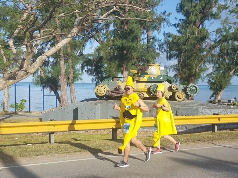 Hui Li, right, slips her way past a historic World War II tank on her way to winning the Best Costume-Female at Saipan Marathon 2019 on March 9, 2019. The Marianas Visitors Authority will award prizes for best tourist costume during the Walk for Tourism 5K in Saipan on May 28, 2021.MVA photo