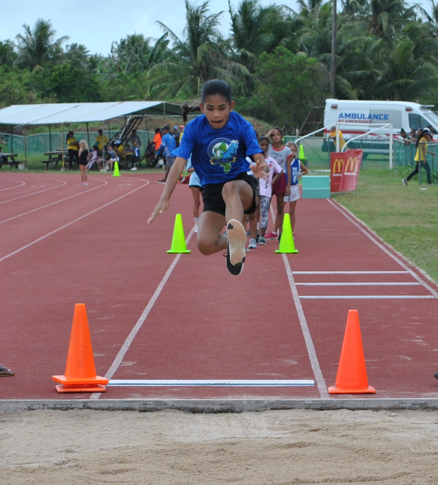 A student soars in the U12 girls high jump event.