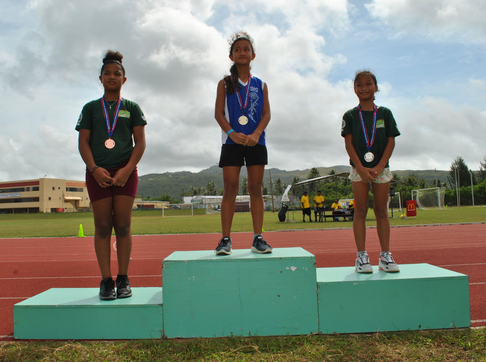Saipan International School’s Beatrice Gross, center, who won the gold medal in the 100m race, poses for a photo with the bronze and silver medalists Oleai’s Alina Esakova, left, and Elena Teigita, right.Photo by James F. Sablan Jr.