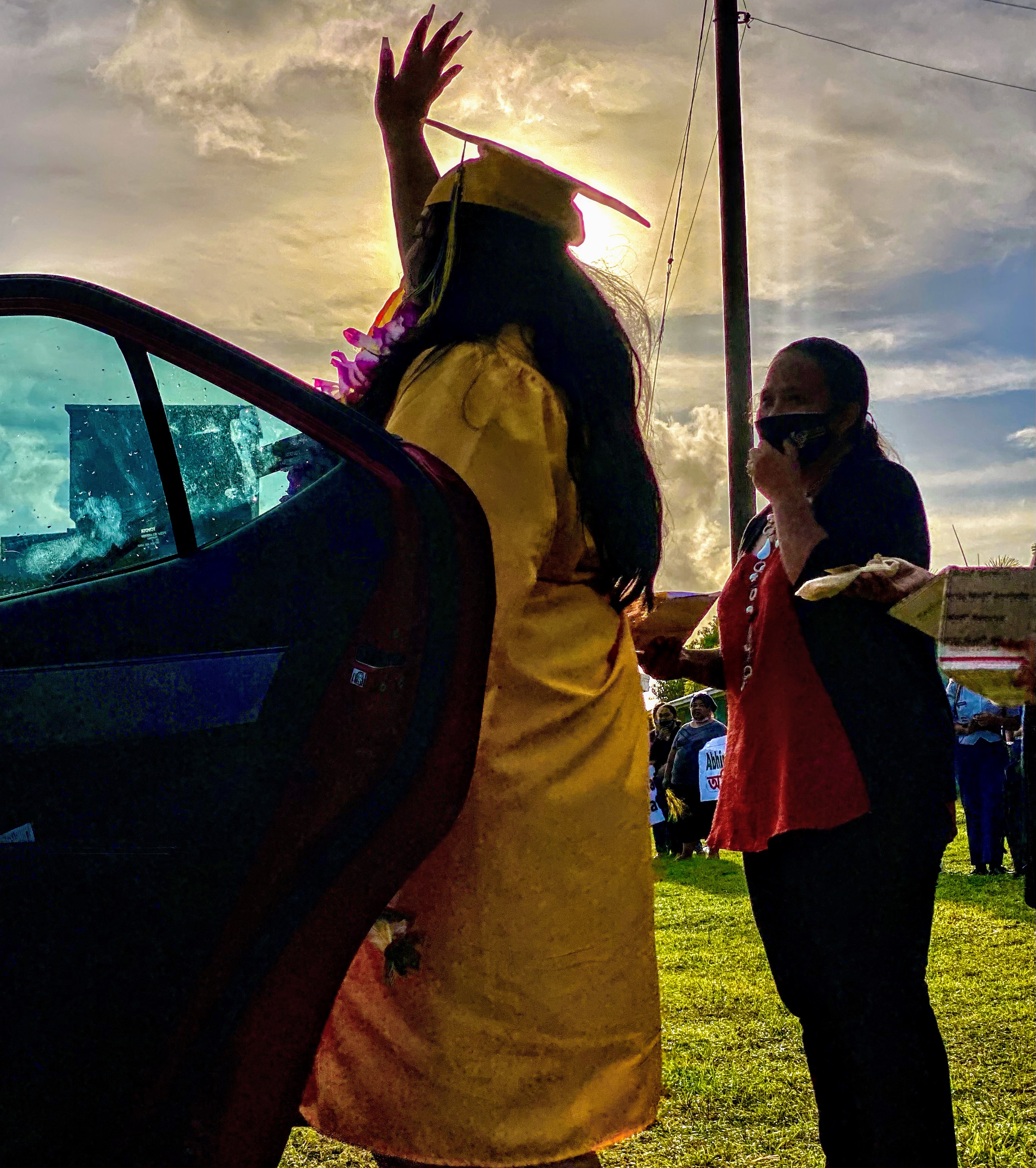 A proud graduate waves while RHI counselor Elvira Mesngon looks on.