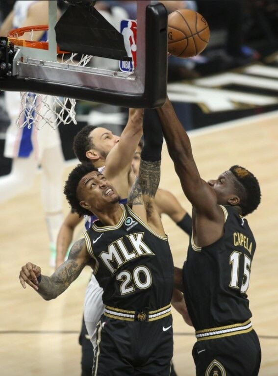 Atlanta Hawks forward John Collins (20) and center Clint Capela (15) reach for a rebound against Philadelphia 76ers guard Ben Simmons (25) in the first quarter during game four in the second round of the 2021 NBA Playoffs at State Farm Arena in Atlanta, Georgia on Monday.