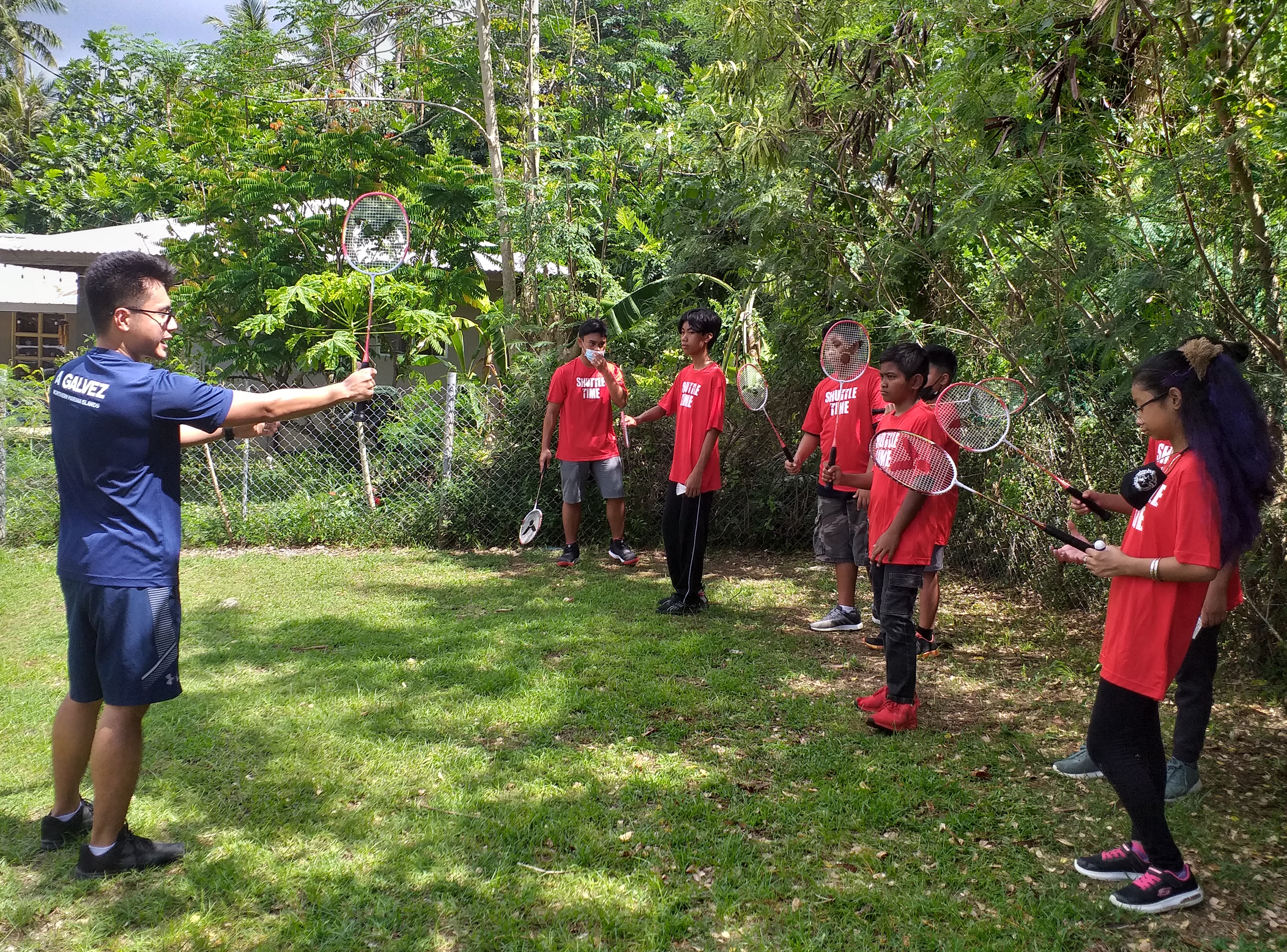 Northern Marianas Badminton Association director Andreau Galvez, left, demonstrates to Green Meadow School students the proper way to hold a racket during a Shuttle Time session at the Falcons’ grounds on Tuesday.
