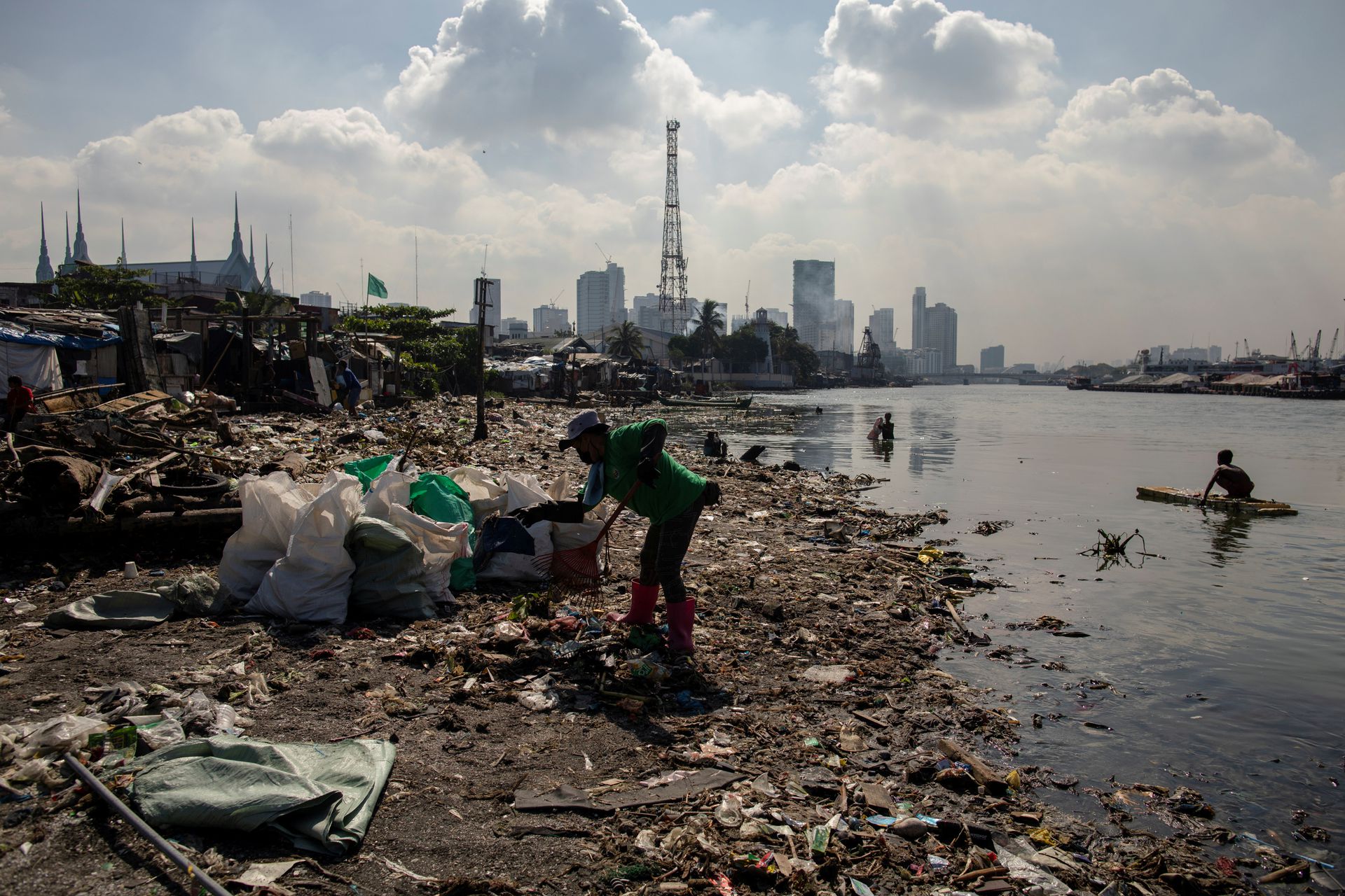 Angelita Imperio, a member of River Warriors, rakes through washed up trash from the heavily polluted Pasig River, at Baseco, Manila on June 18, 2021.