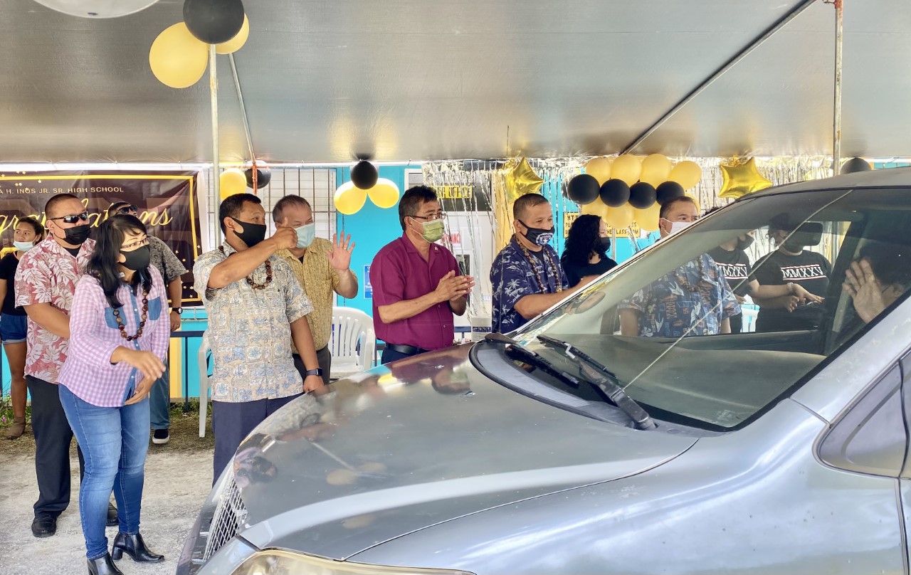 Rota and education officials congratulate  a promoted student during the drive-thru ceremony.