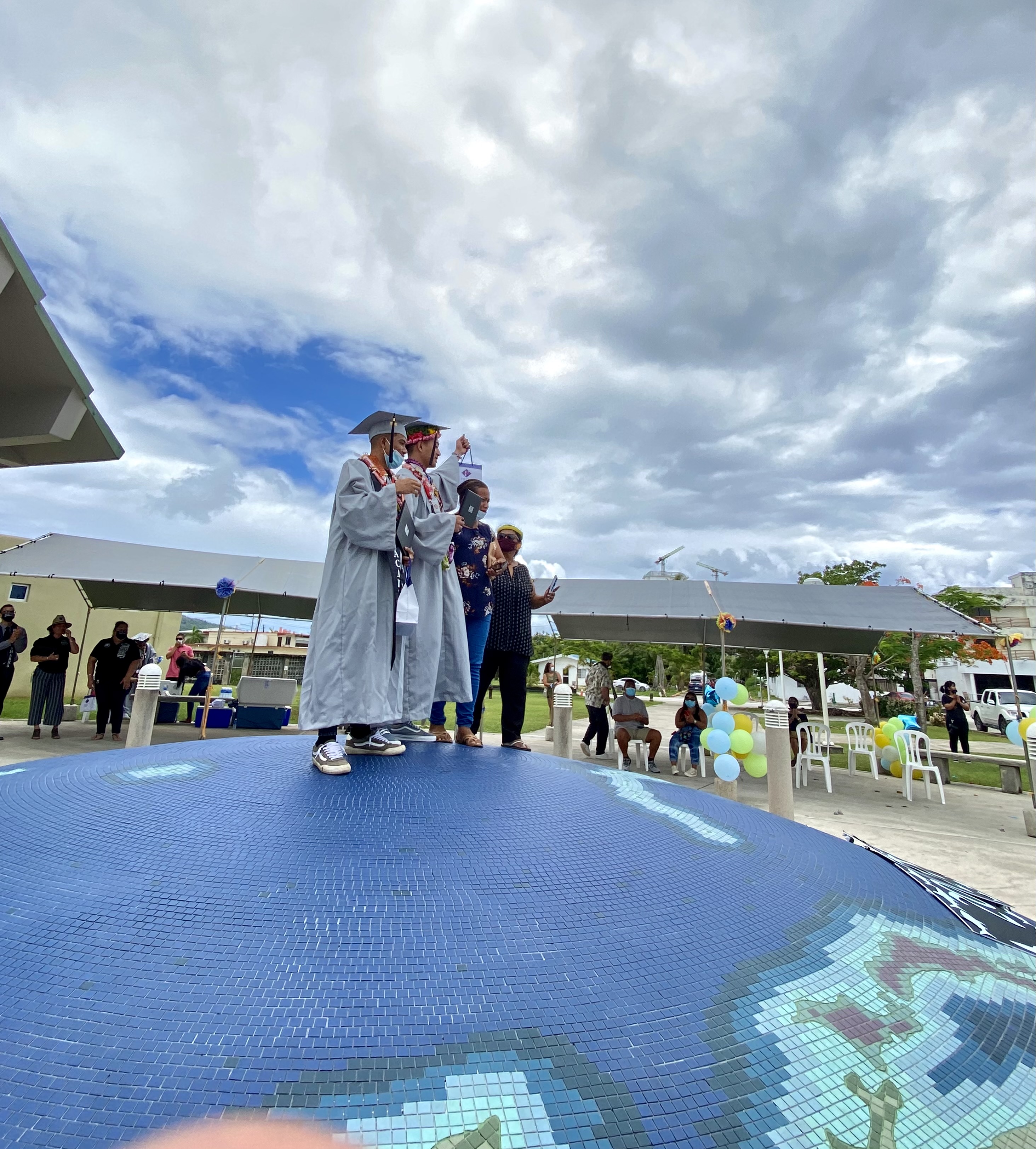 Two graduates pose for a photo with a friend.