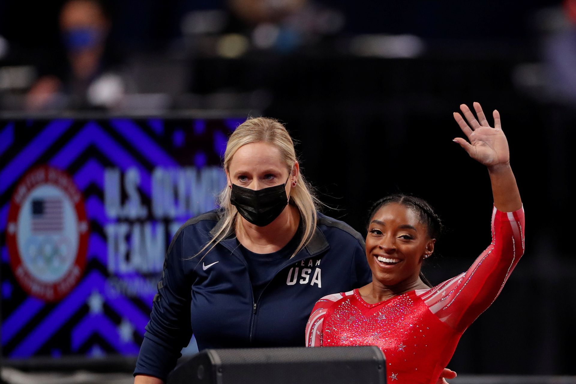 Simone Biles waves as she walks with her coach Cecile Landi after competing on the floor at the U.S. Women's Olympic Gymnastics trials in St Louis, Missouri on June 27, 2021. 