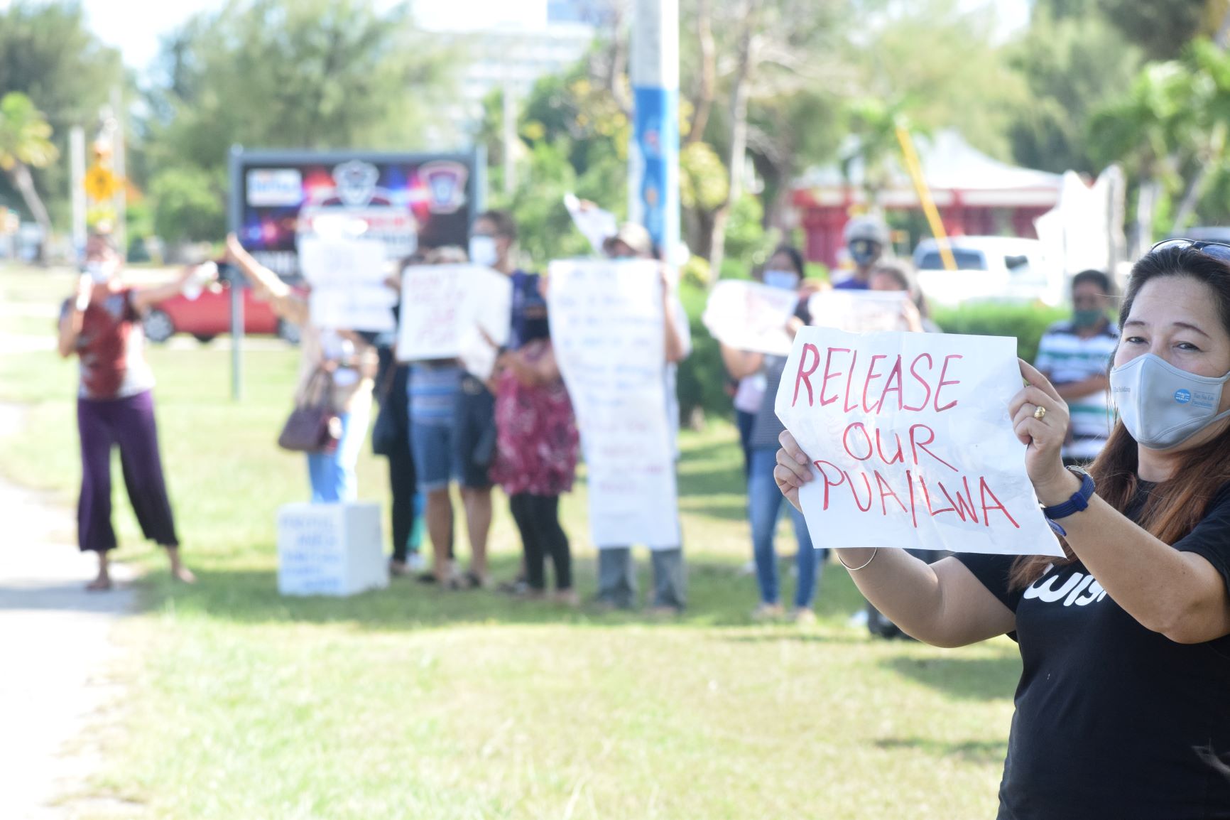 A PUA applicant, right,  holds a placard during a rally at Kilili Beach on Thursday.