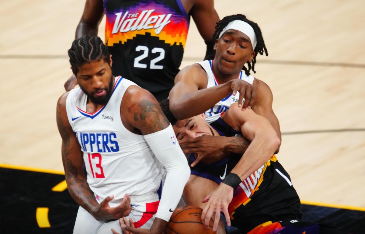 Los Angeles Clippers guard Paul George (13) and Terance Mann (right) battle for a rebound against Phoenix Suns guard Devin Booker in the first half during game one of the Western Conference Finals for the 2021 NBA Playoffs at Phoenix Suns Arena on June 20, 2021.