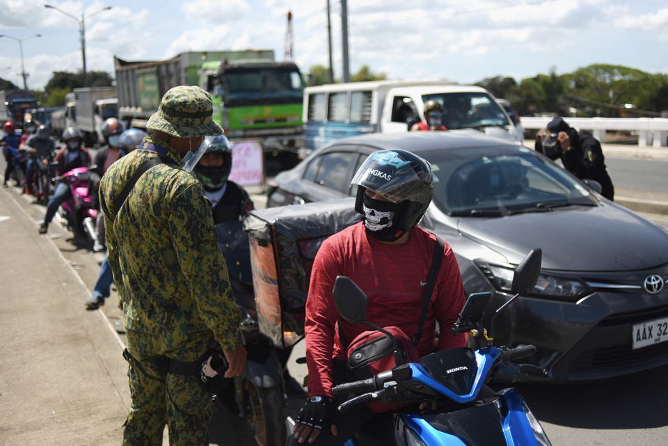 A police officer mans a checkpoint as the country's capital returns to stricter lockdown measures amid rising coronavirus disease cases in Quezon City, Metro Manila on March 29, 2021. 