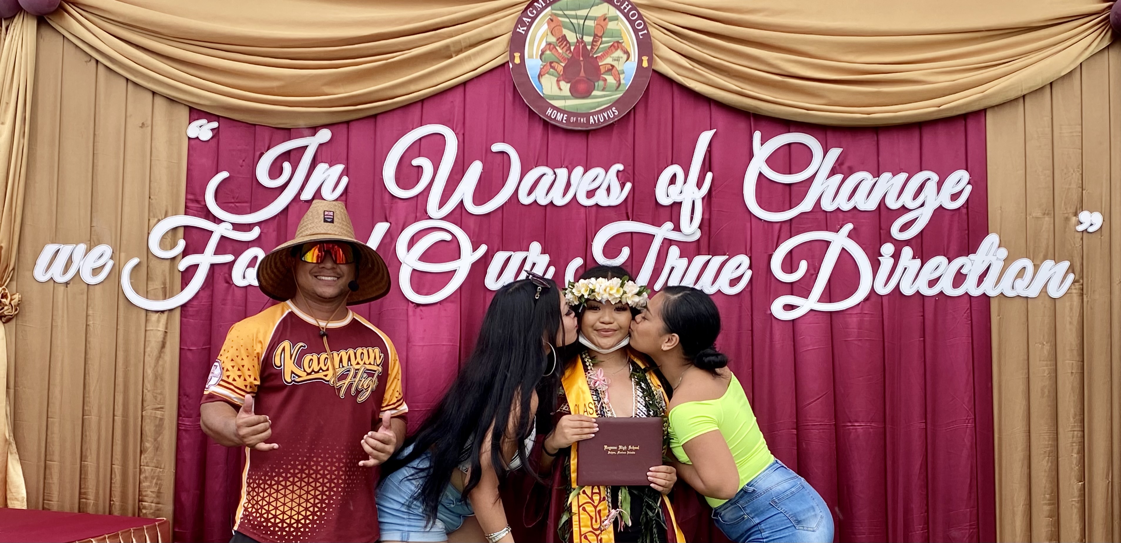 A graduating student receives kisses from well-wishers.