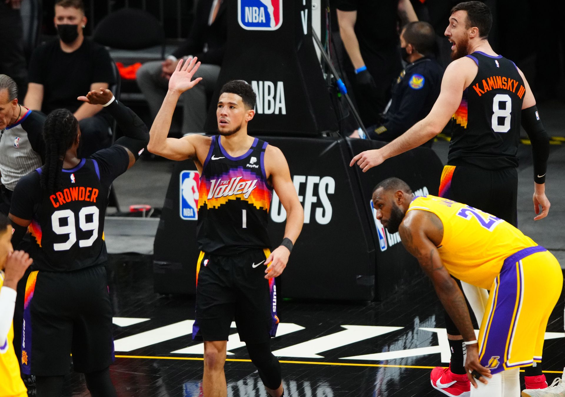 Phoenix Suns guard Devin Booker (1) celebrates with Jae Crowder (99) as Los Angeles Lakers forward LeBron James (23) looks on in the first half during game five in the first round of the 2021 NBA Playoffs at Phoenix Suns Arena in Phoenix, Arizona on June 1, 2021.