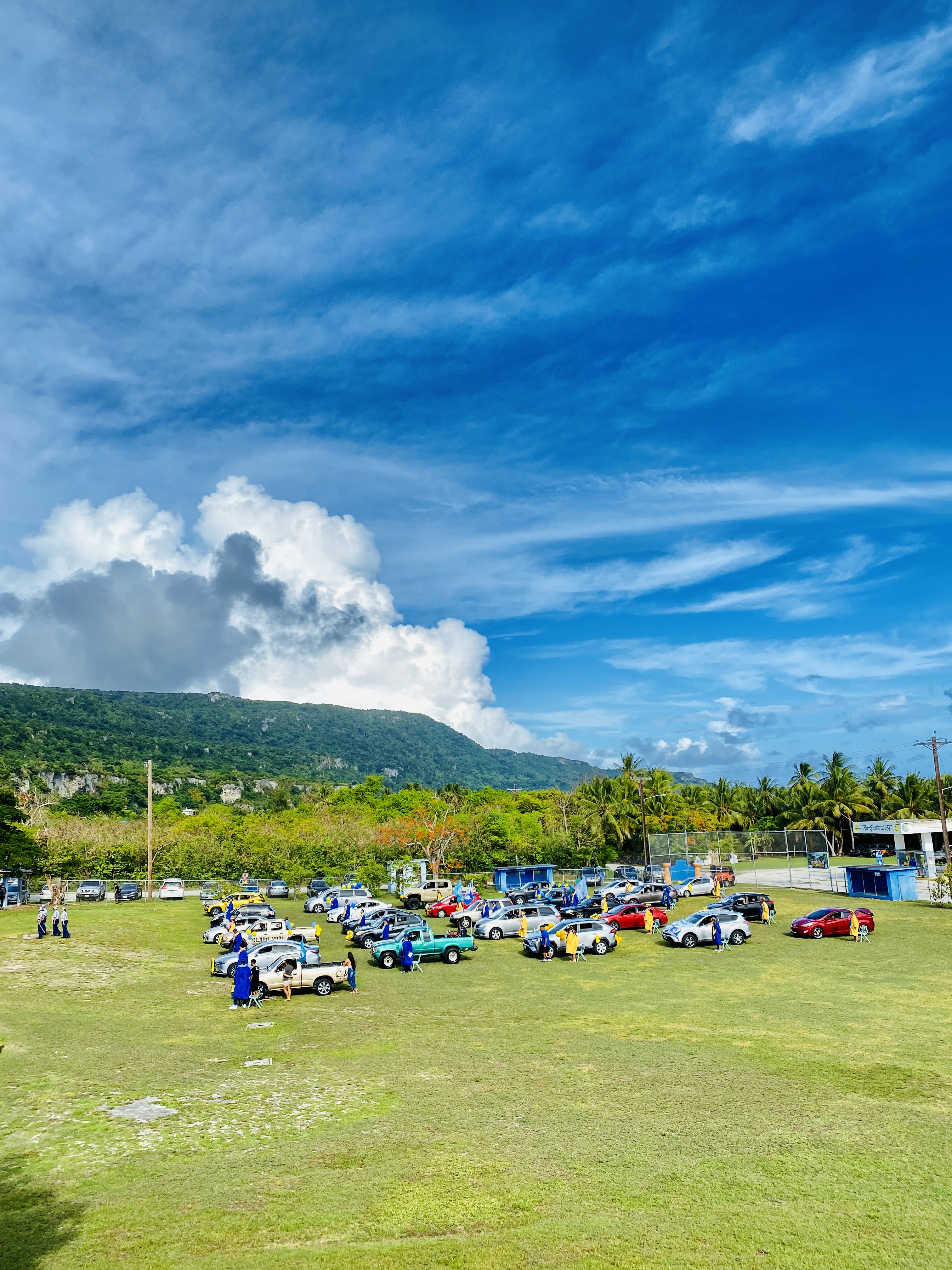 The seniors stand near their parked vehicles at the start of the graduation ceremony.