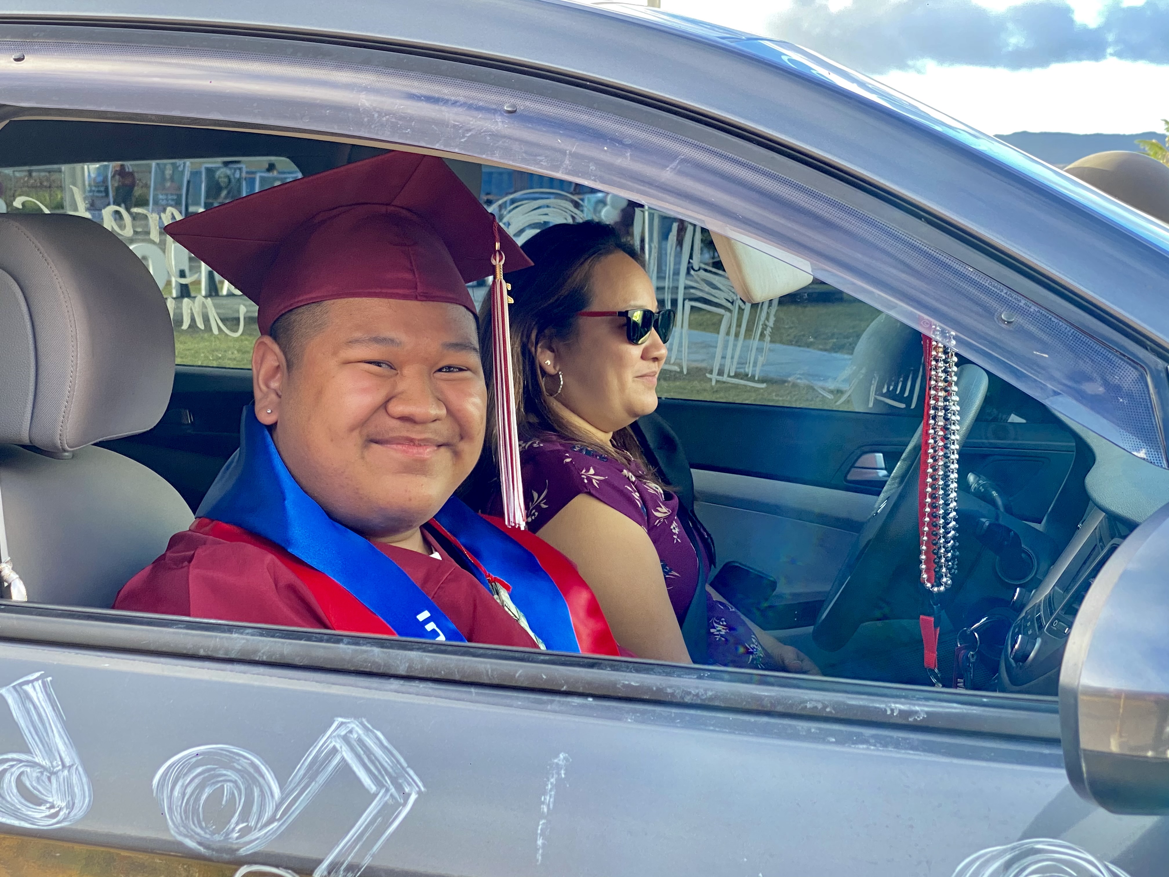 A graduating member of the Class of 2021 smiles during the drive-thru ceremony.