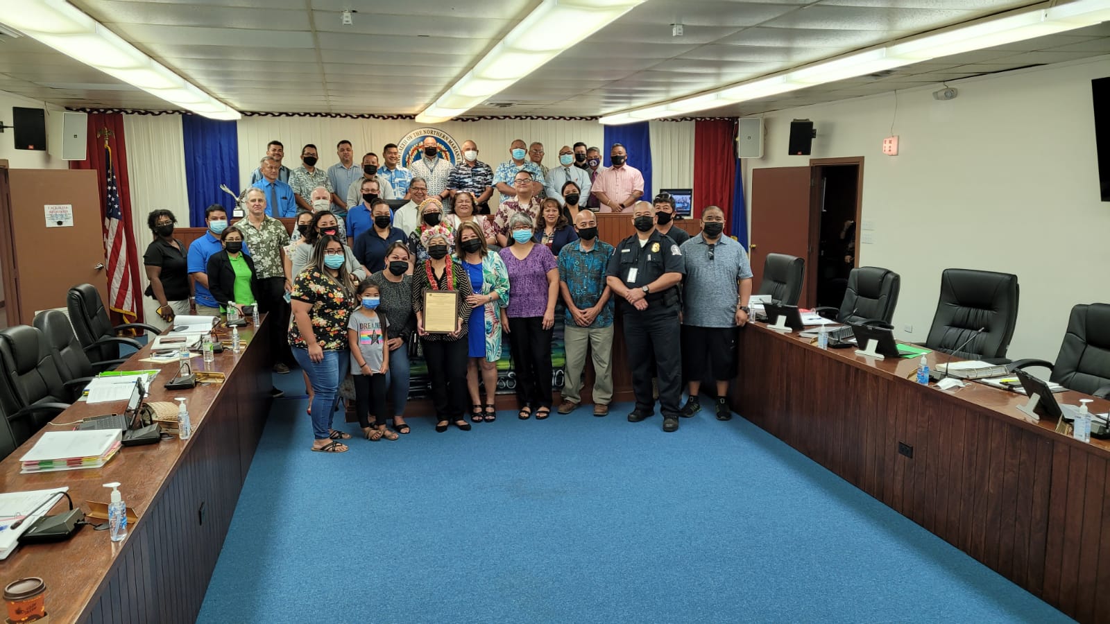 Micronesian Legal Services Corp. paralegal Maria Palacios Muna holds a framed copy of House Resolution 22-6 as she poses for a photo with her family members,  other MLSC personnel and members of the 21st House on Wednesday in the House chamber.