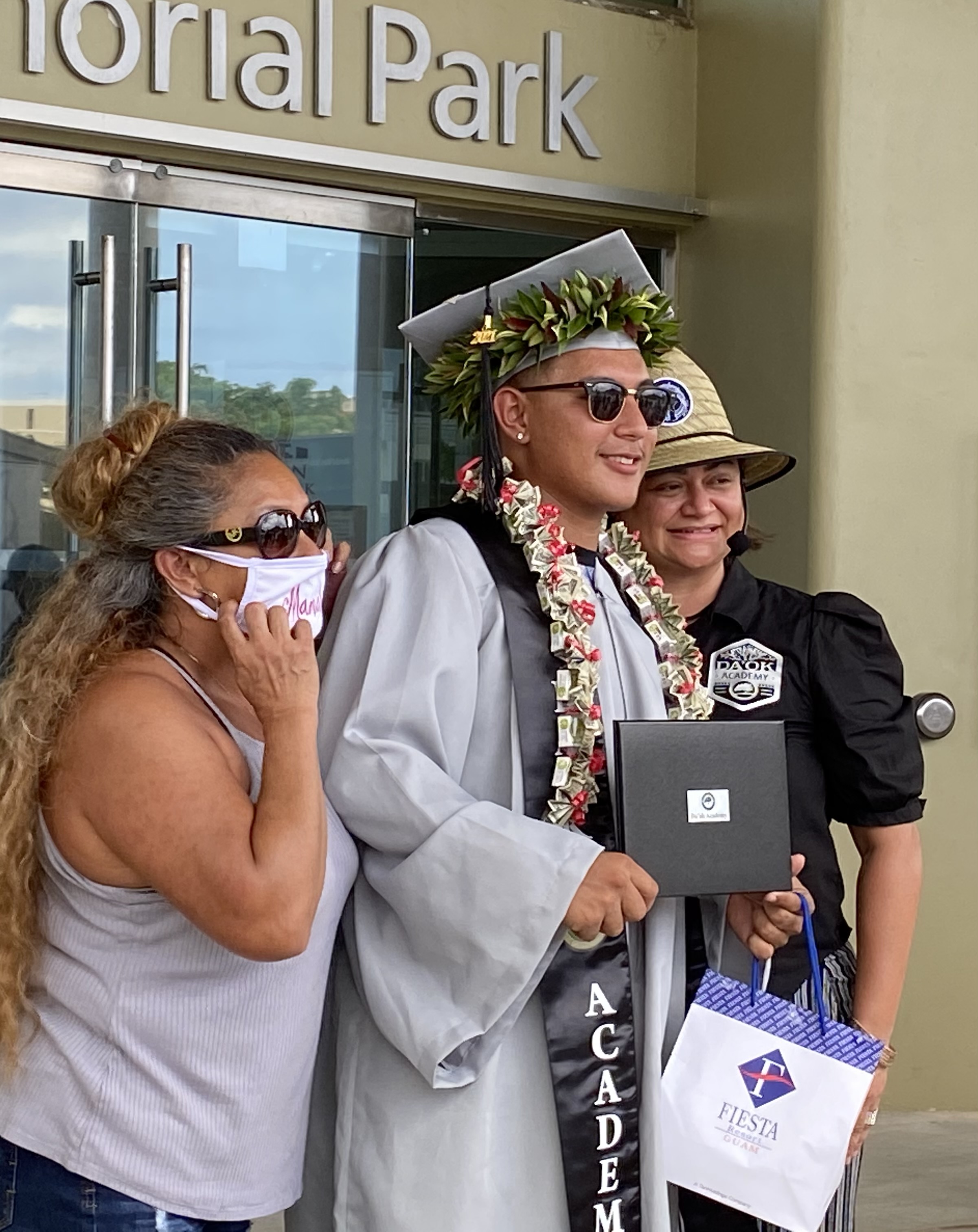 A proud graduate with his mother and school principal.